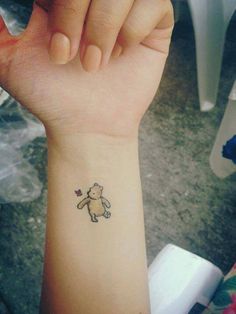 a small wrist tattoo with a teddy bear on it