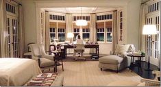 a living room filled with lots of furniture and windows next to each other on either side of a bed