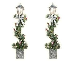 two christmas lights with bows and holly on them are hanging from the side of a wall