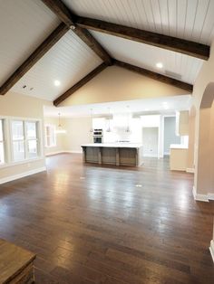 an empty living room with wood floors and exposed beams on the ceiling is seen in this image