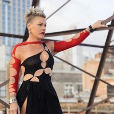 a woman standing on top of a metal structure with her arm extended and holding a knife in one hand