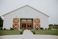 a large white barn with wooden doors and windows