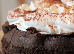 a chocolate cake with white frosting and marshmallows on top is shown