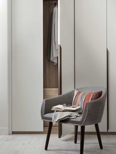 a grey chair sitting in front of a closet