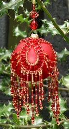 a red ornament hanging from a tree in front of some green leaves and branches