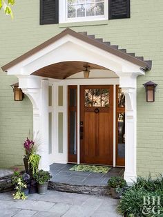 the front door of a house with two potted plants on the steps and an entry way leading to it