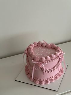 a pink cake sitting on top of a white table