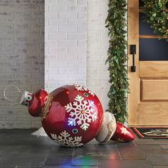 a red christmas ornament sitting on the ground next to a door