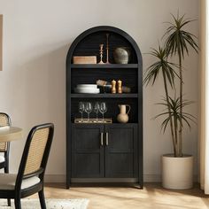 a black bookcase with wine glasses and plates on it in the corner of a dining room