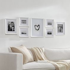 a living room with white walls and pictures on the wall above the couch, along with a coffee table