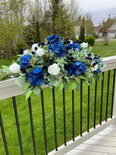 a bouquet of blue and white flowers sitting on top of a metal railing next to grass