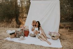 a man and woman sitting on top of a blanket