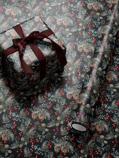 a present wrapped in red ribbon sitting on top of a floral print wrapping paper with a bow