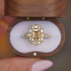 an engagement ring in a wooden box with a diamond center stone and baguets