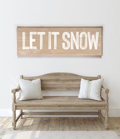 a wooden bench sitting in front of a wall with a sign that says let it snow