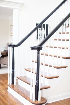 a white staircase with black railing and wood handrails in a home setting on the hardwood flooring