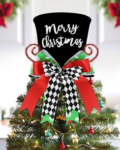 a christmas tree with a black top hat and red ribbon on it that says merry christmas