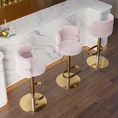 three pink velvet bar stools in front of a white marble counter with gold legs