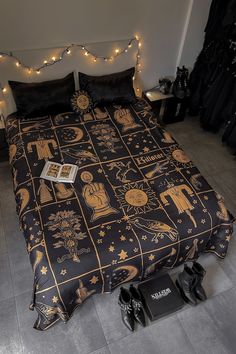 a bed covered in black and gold sheets with shoes on the floor next to it