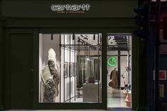 a store front at night with its lights on and the door open to show clothing