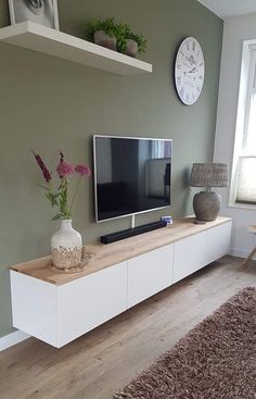 a living room with white furniture and a flat screen tv on top of a entertainment center