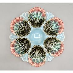 four seashells on a blue plate with pink, green and orange designs in the center