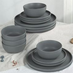 a set of gray dinnerware on a white table cloth