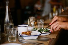 a person is cutting food on a plate with a knife and fork at a table