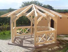 a small wooden gazebo sitting on top of a stone patio next to a building