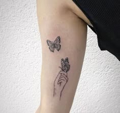 a woman's arm with two butterflies on it and one is holding the other