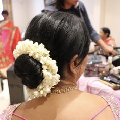 the back of a woman's head with flowers in her hair and other people standing around