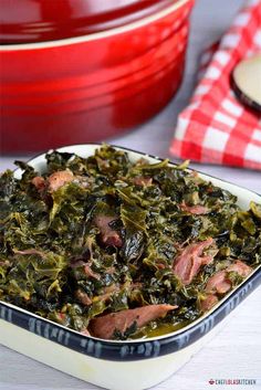 a casserole dish filled with ham and collard greens on a white table