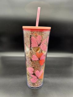 the tumbler cup is decorated with pink and orange butterflies on gold flecks