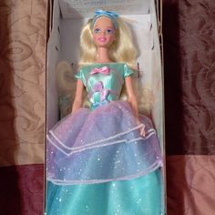 a barbie doll in a box on a bed