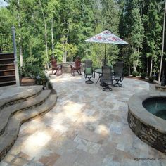 a patio with chairs and an umbrella next to a hot tub in the middle of it