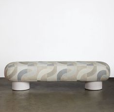 a white bench sitting on top of a cement floor next to a gray and white wall