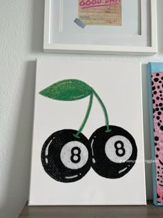 two black and white balls with green leaves on them are next to a pink wall