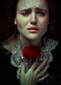 a woman with blood on her face holding a red rose