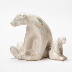 a white ceramic figurine of a bear sitting on the ground with its baby