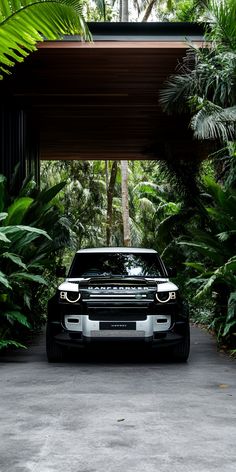 a black range rover parked under a canopy in the middle of some tropical plants and trees