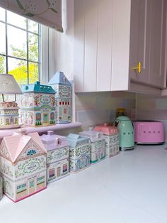 there are many toy houses on the counter in this kitchen, and one has a pink toaster oven