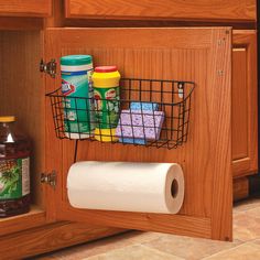 the kitchen cabinet door is open and has various items in it, including rolls of toilet paper