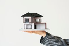 a person holding up a model house in their hand