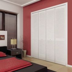 a bedroom with red walls and white closets next to a black bed in front of a window