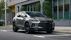 a silver chevrolet suv is parked on the side of the road in front of a building