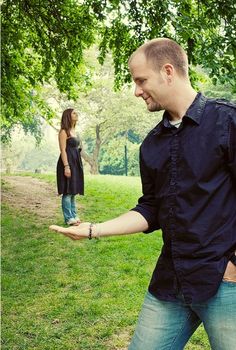 a man is holding out his hand to a woman in the park while she stands behind him