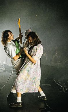 two people on stage with guitars in their hands