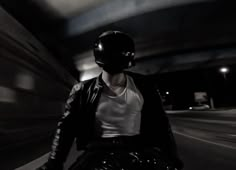 a man riding on the back of a motorcycle down a street next to a tunnel