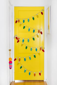 a bright yellow door with christmas lights on the front and side hanging from it's sides