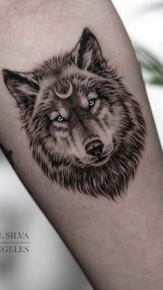 a black and white wolf tattoo on the arm